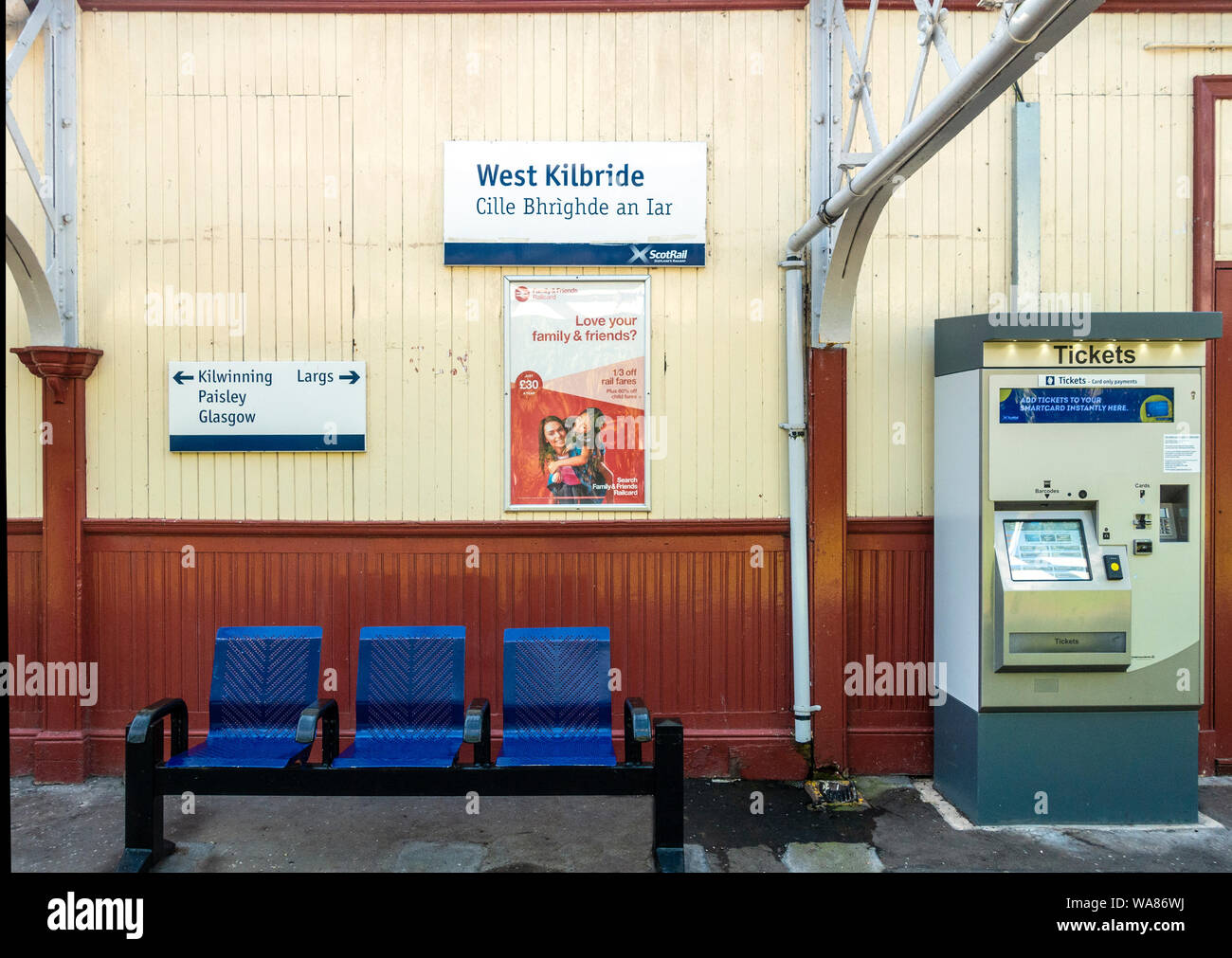 Detail der Teil der Plattform unter dem Vordach an der West Kilbride station (erbaut 1900). Bi-lingual Schild mit Gälisch. Direktionale Zeichen, Werbung post Stockfoto