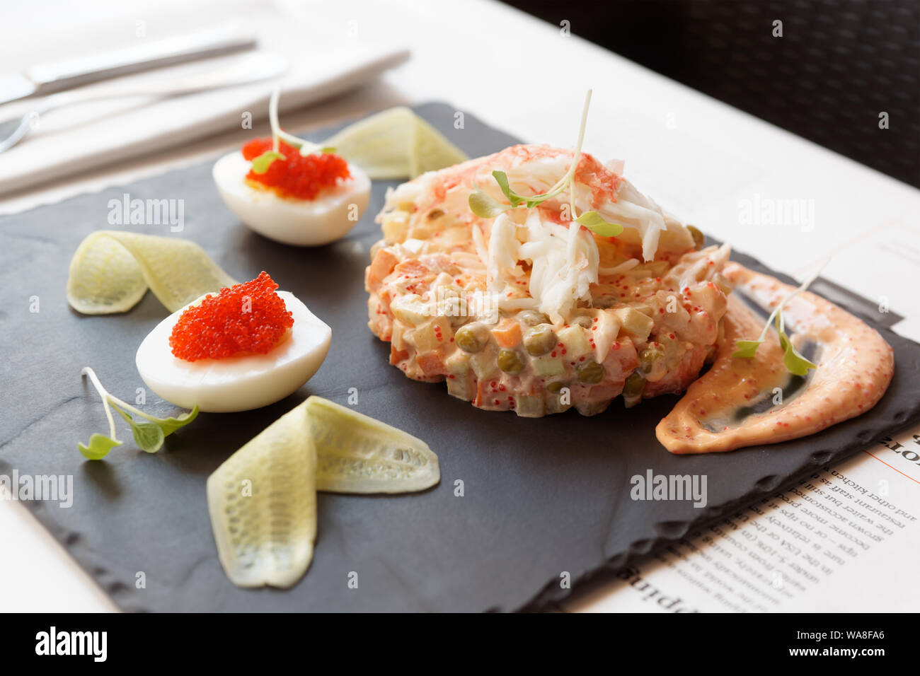 Russischer Salat mit Krabbenfleisch und fliegende Fische roe auf schiefer Platte Stockfoto