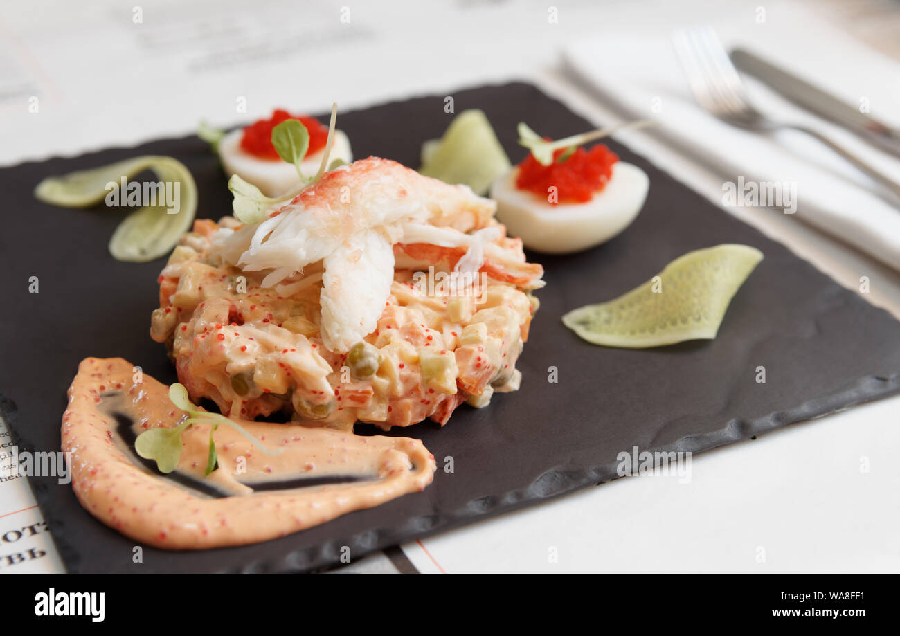 Russischer Salat mit Krabbenfleisch und tobico Fischrogen Soße auf schiefer Platte Stockfoto