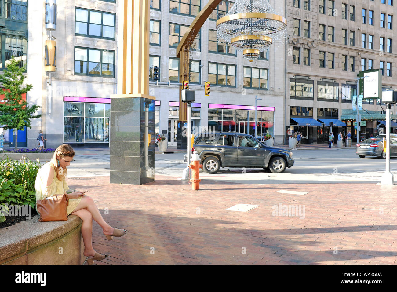 Frau sitzt im Playhouse Square Theatre District in der Nähe des größten Kronleuchters im Freien der Welt an der Euclid Avenue in Cleveland, Ohio, USA. Stockfoto