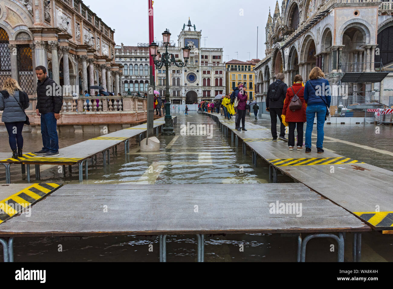 Menschen zu Fuß auf erhöhten Plattformen während der Acqua Alta (hohe Wasser) Fall, Piazzetta di San Marco, Venedig, Italien Stockfoto