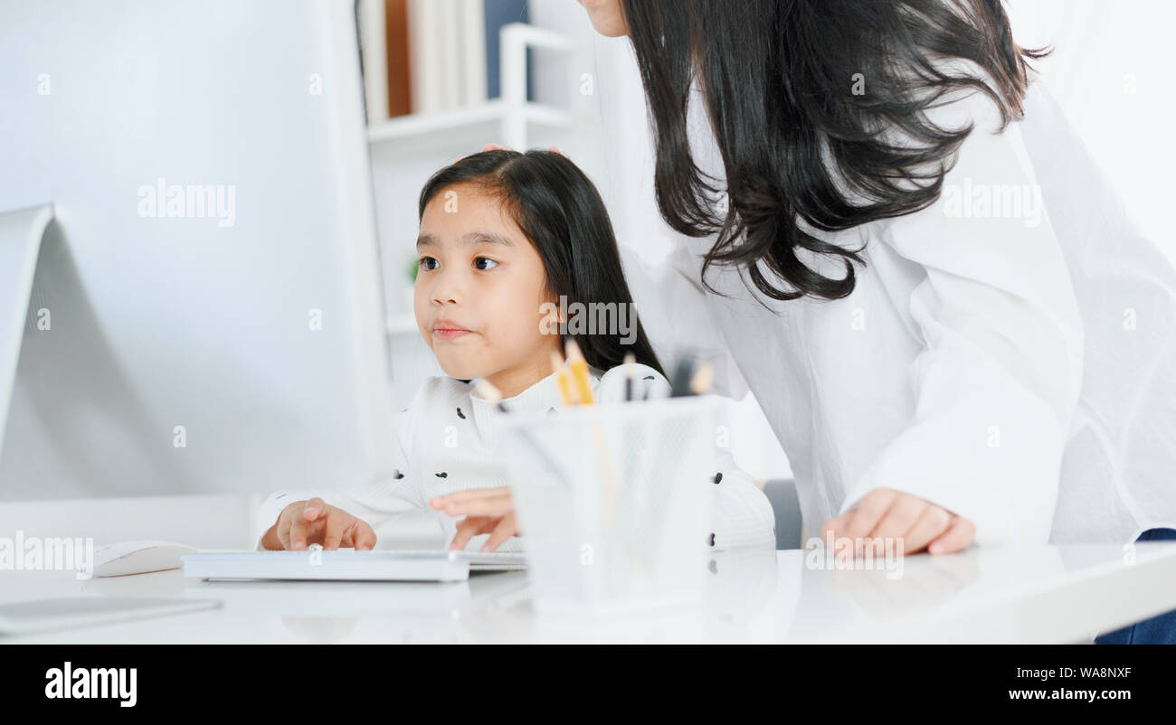 Gerne kleine Mädchen auf Computer mit ihrer Mutter Stockfoto