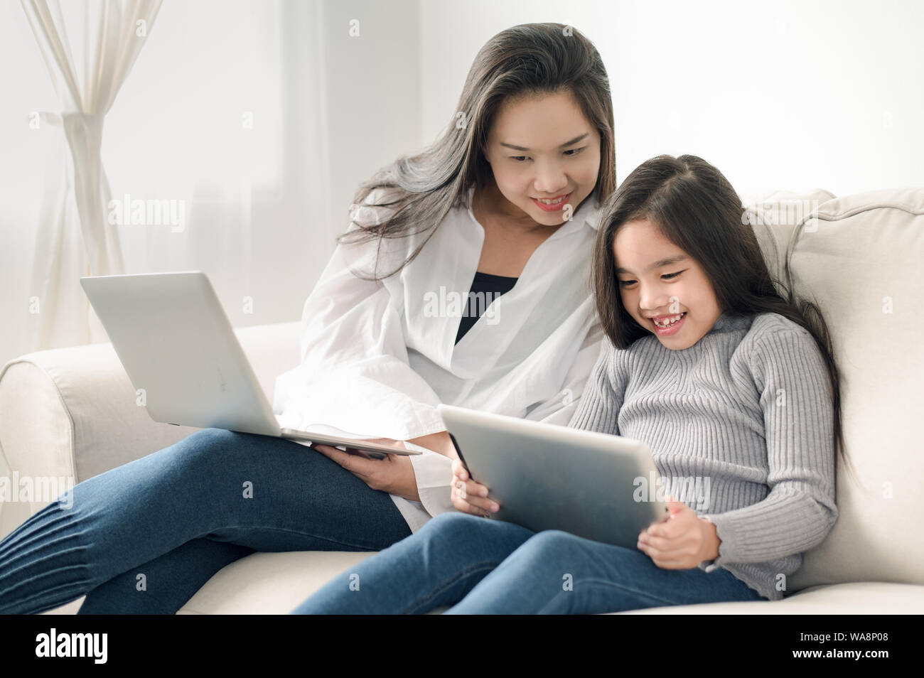 Glückliche Mutter und Tochter mit Laptop- und Tablet-PC Stockfoto