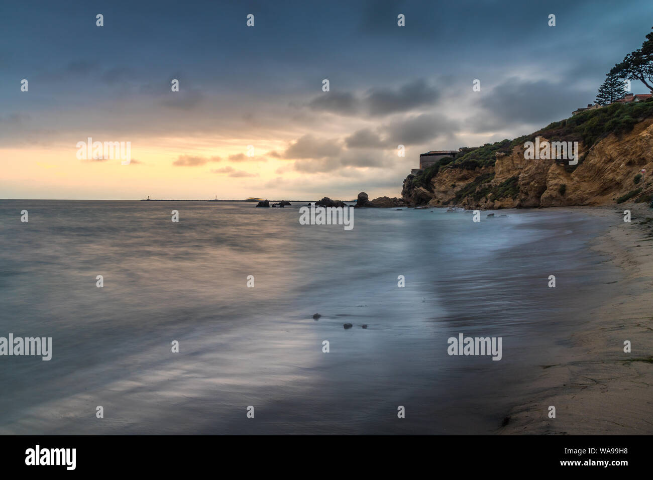 Schöne lange Belichtung geschossen von kleinen Corona Del Mar Strand bei Sonnenuntergang mit sanften Wellen auf das Ufer und hohen Klippen im Hintergrund, Coro Stockfoto