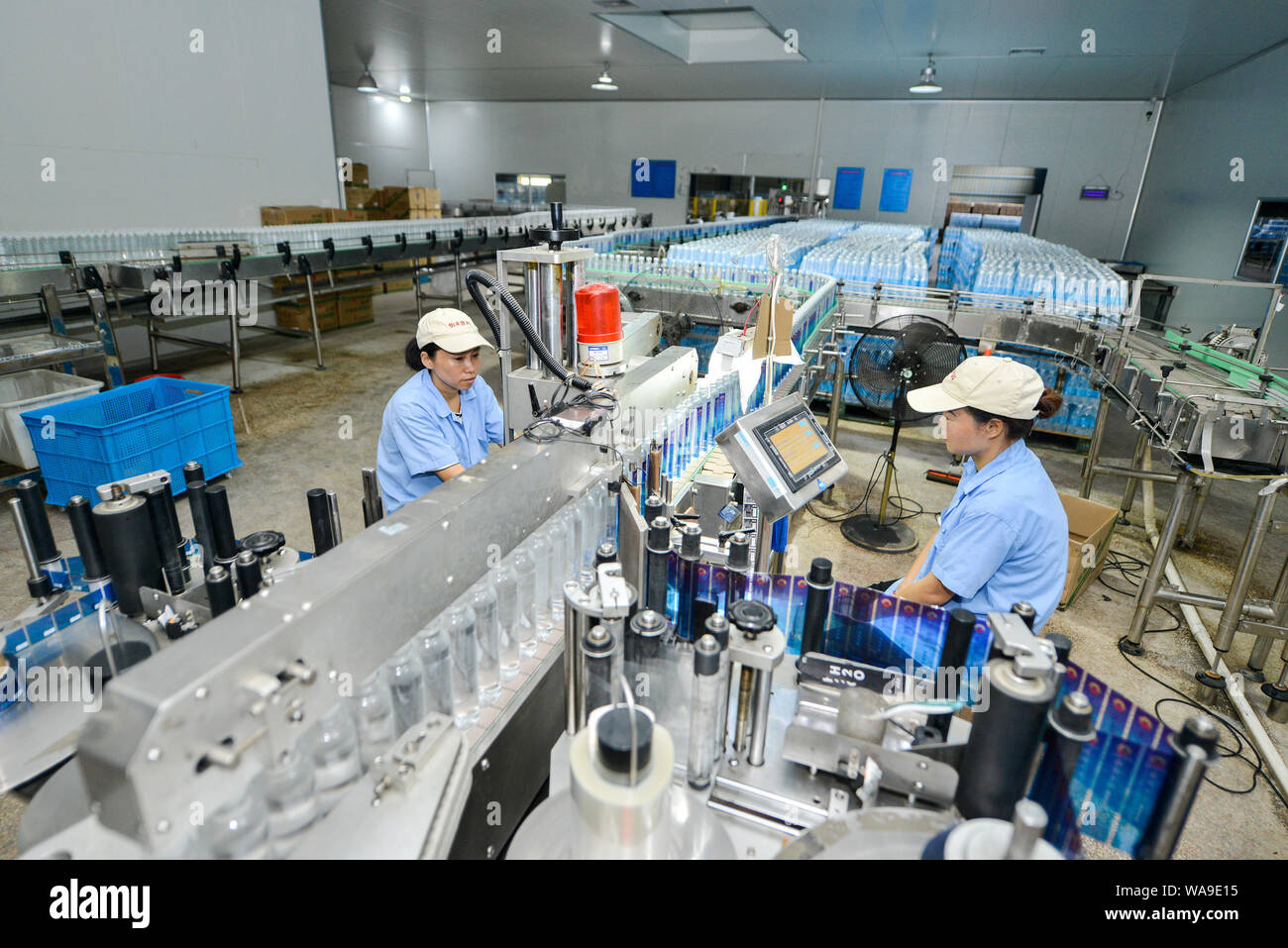 Chinesische Arbeiter produzieren Flaschen Mineralwasser auf einem Fließband in einer Anlage in Changxing Grafschaft, Stadt Huzhou, der ostchinesischen Provinz Zhejiang, 28 J Stockfoto
