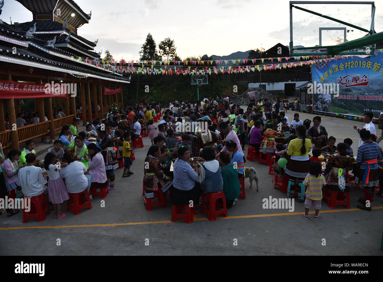 Chinesische ältere Frauen von Miao ethnische Gruppe und ihre Enkelkinder Essen gekochten Reis und andere Nahrungsmittel, die von den chinesischen Mädchen von Miao ethnische Gruppe gesammelt tragen Stockfoto