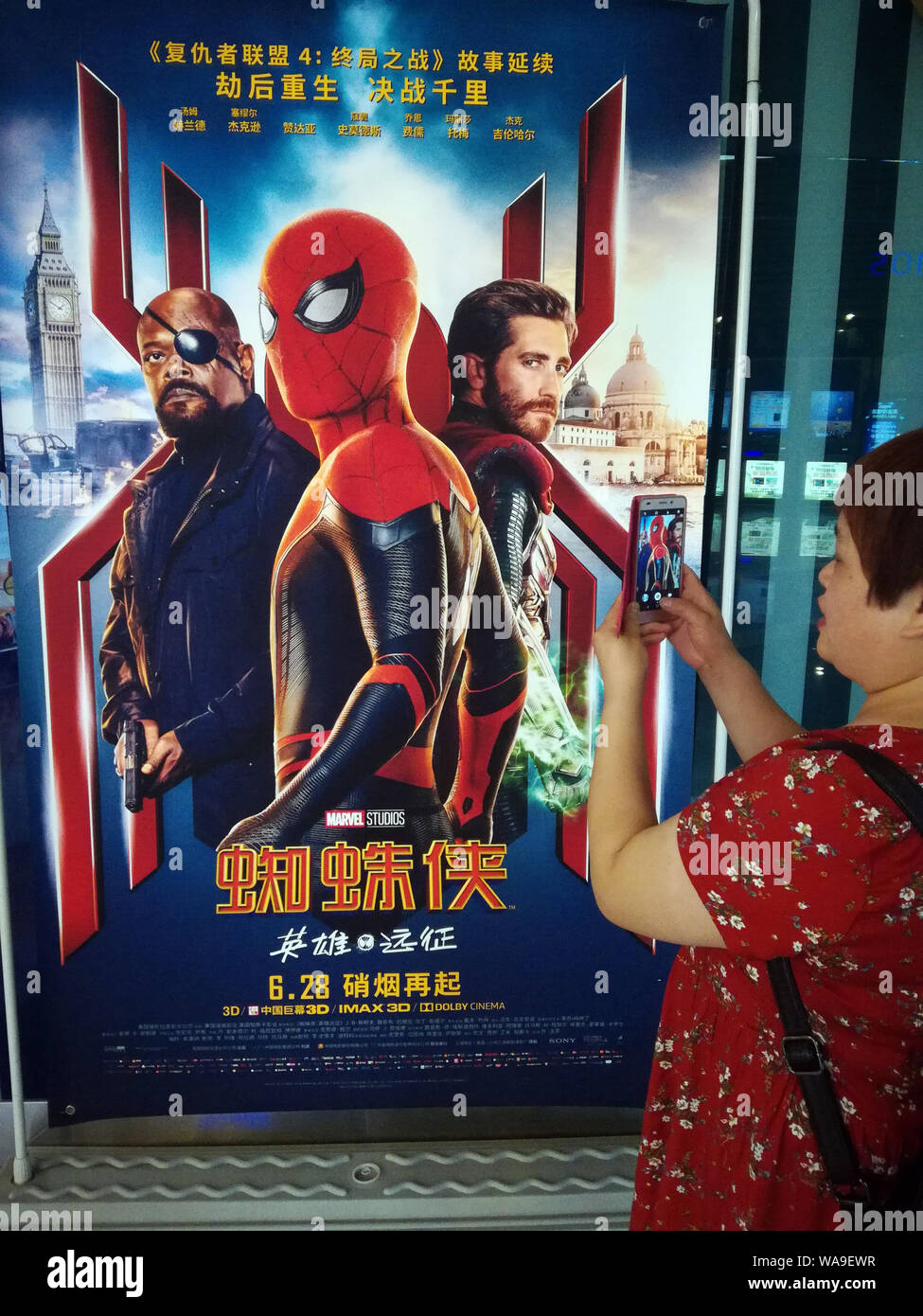 ---- Eine filmgoer wartet vor einem Plakat der amerikanischen Superhelden film 'Spider-Man: Weit weg von Zuhause" in einem Kino in Kunshan City, Central China Hube Stockfoto