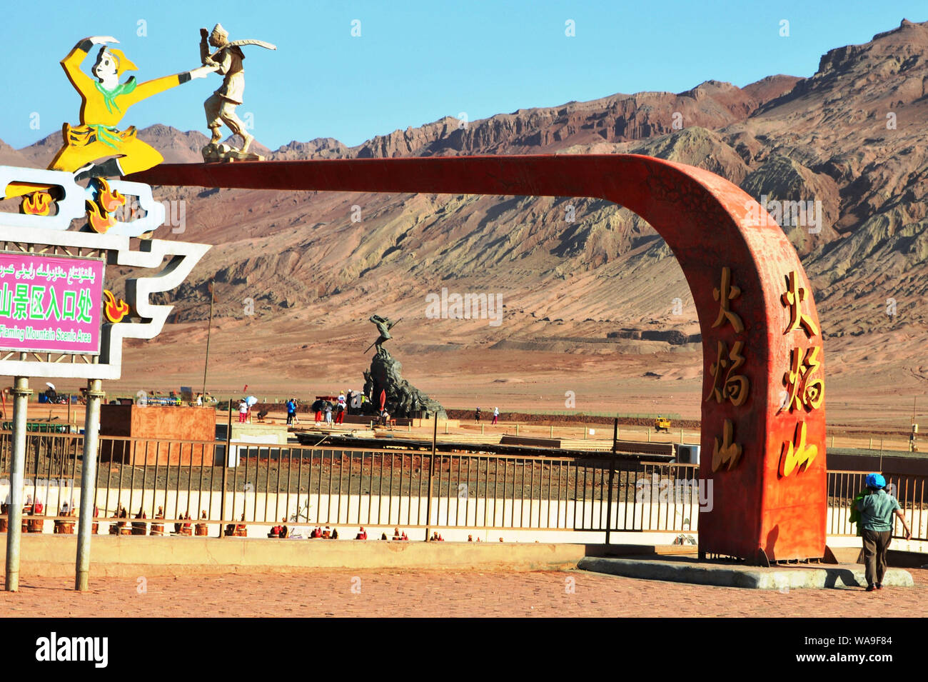 Touristen posieren für Fotos mit den Sehenswürdigkeiten Skulptur am Fuße des Huoyan (Flaming) Berg in Turpan Becken, im Nordwesten Chinas Xinjiang Uygur au Stockfoto