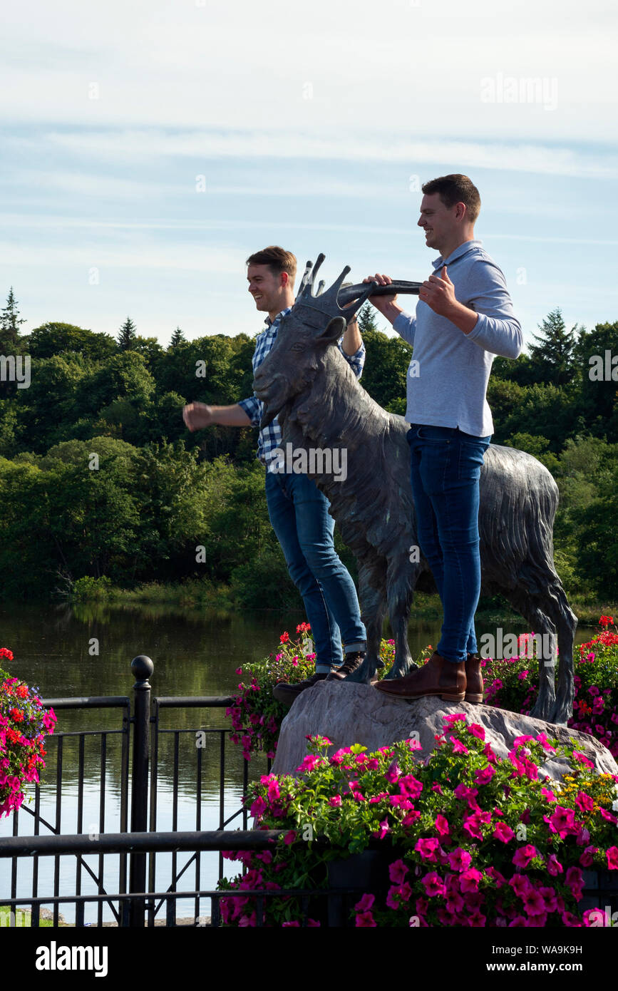 Touristen haben Spaß beim Fotografieren auf der King Puck Ziegenstatue während der Puck Fair - dem ältesten irischen Festival in Killorglin, County Kerry, Irland Stockfoto