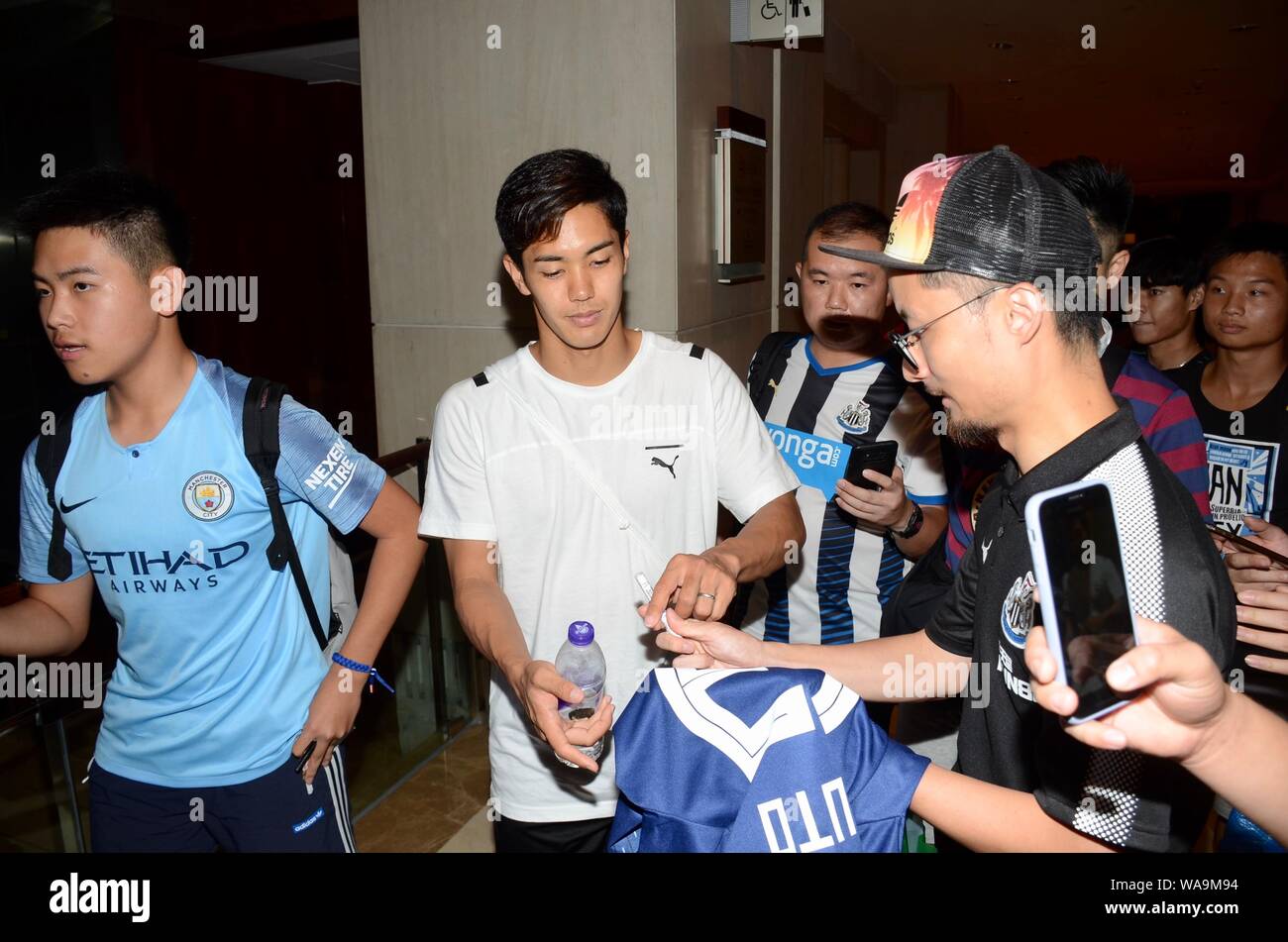 Yoshinori Muto von Newcastle United F.C. der englischen Liga Champions interagiert mit Fans, da verlässt er ein Hotel vor der Premier League Asien Trophy 201 Stockfoto