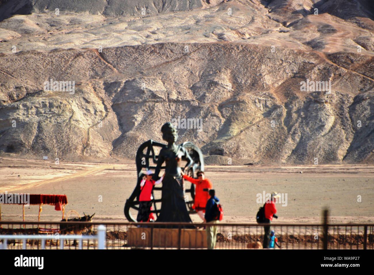 Touristen posieren für Fotos mit den Sehenswürdigkeiten Skulptur am Fuße des Huoyan (Flaming) Berg in Turpan Becken, im Nordwesten Chinas Xinjiang Uygur au Stockfoto