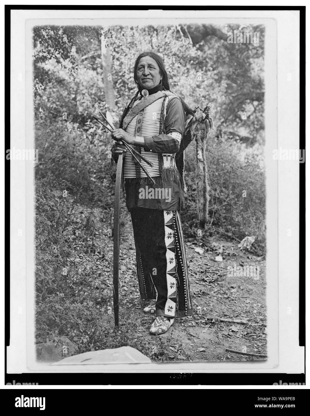 Chief stehender Bär (evtl. Luther Standing Bear) in voller Länge Porträt, stehend, mit leicht nach links, halten den Bogen und die Pfeile Stockfoto