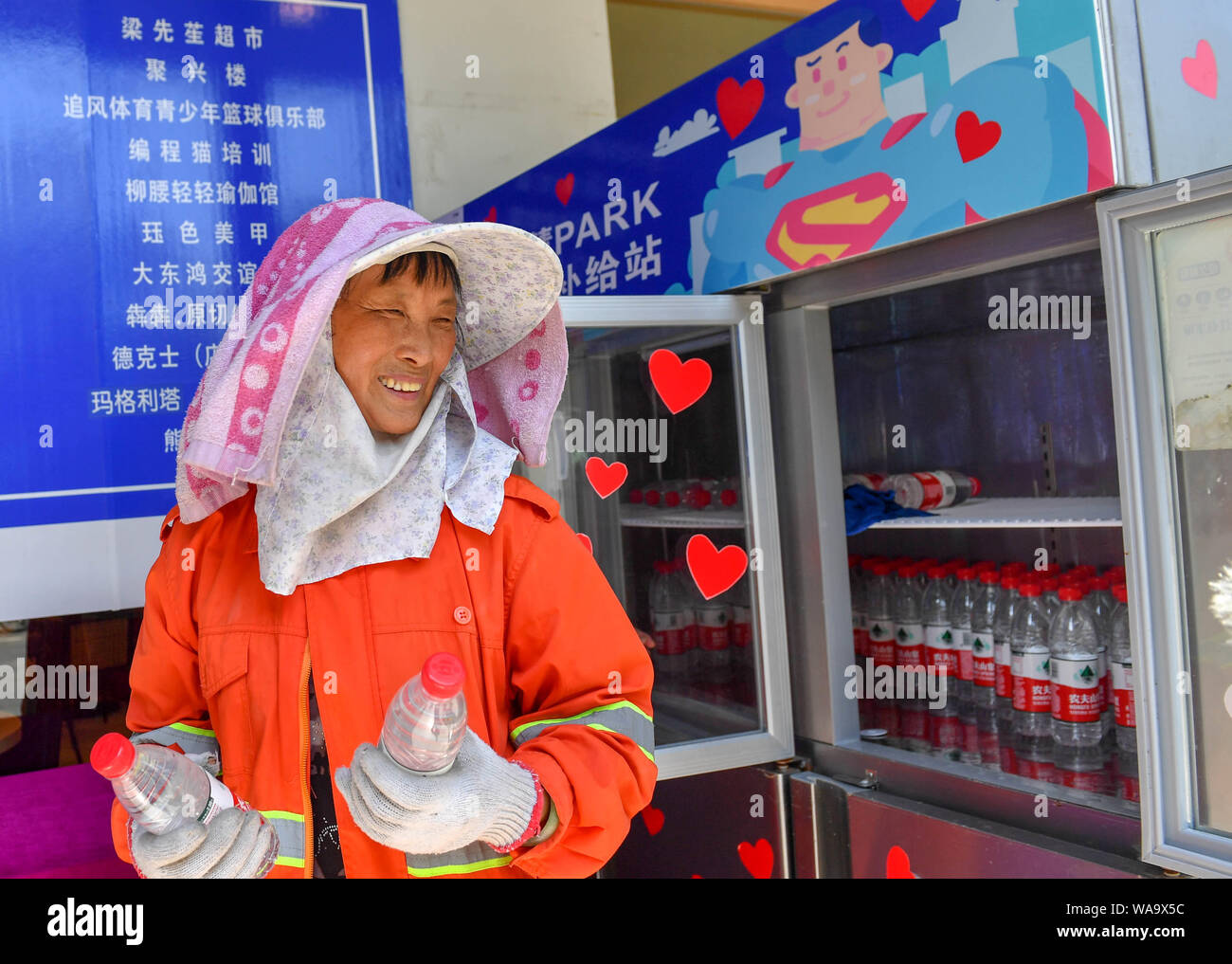 Eine Abwasserentsorgung Arbeiter nehmen Flaschen Wasser aus der Gemeinschaft Kühlschrank bei Straße in Hangzhou Yuhang Bezirk, Stadt, der ostchinesischen Provinz Zhejiang, 25. Stockfoto