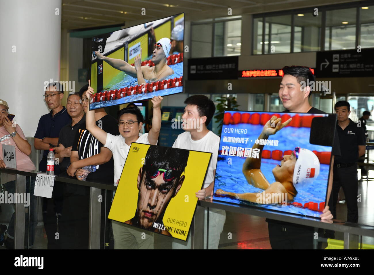 Chinesische Fans halten Bilder der Chinesischen schwimmen Olympiasieger Sun Yang, wie Sie an der Hangzhou Xiaoshan International Airport in Hangzhou city warten. Stockfoto