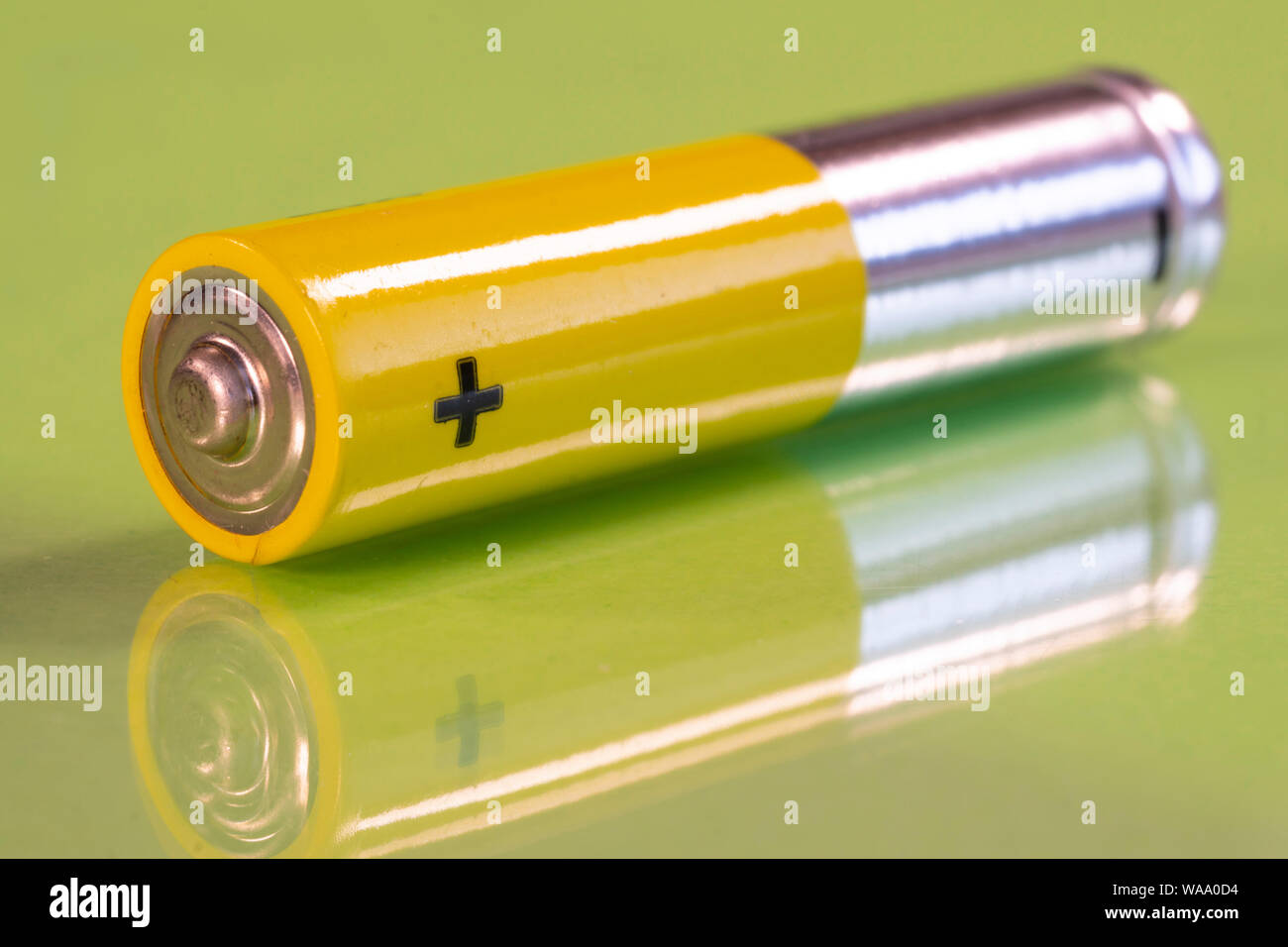 AAA-Batterie ist auf eine reflektierende Oberfläche grün gesehen. Detailansicht von der plus Seite der Batterie. Stockfoto