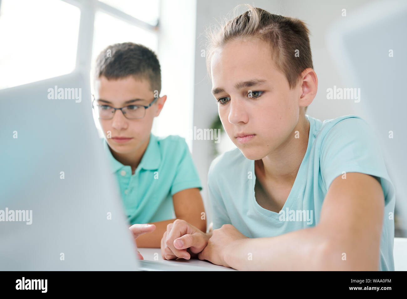 Zwei clevere Schüler sitzen, Schreibtisch vor Laptop Display Stockfoto