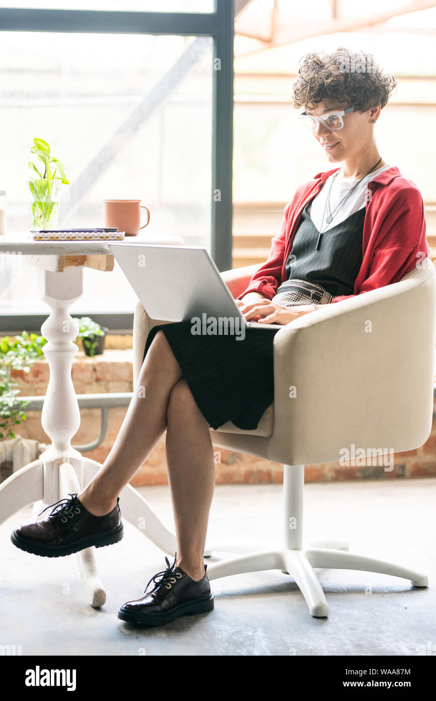 Junge elegante Geschäftsfrau, Computer arbeiten im Sessel sitzt Stockfoto