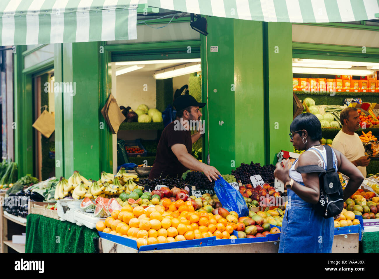 London/Großbritannien - 16. Juli 2019: Frau kaufen Obst an der Brixton Essen Marktstand mit verschiedenen Arten von Obst und Gemüse Stockfoto