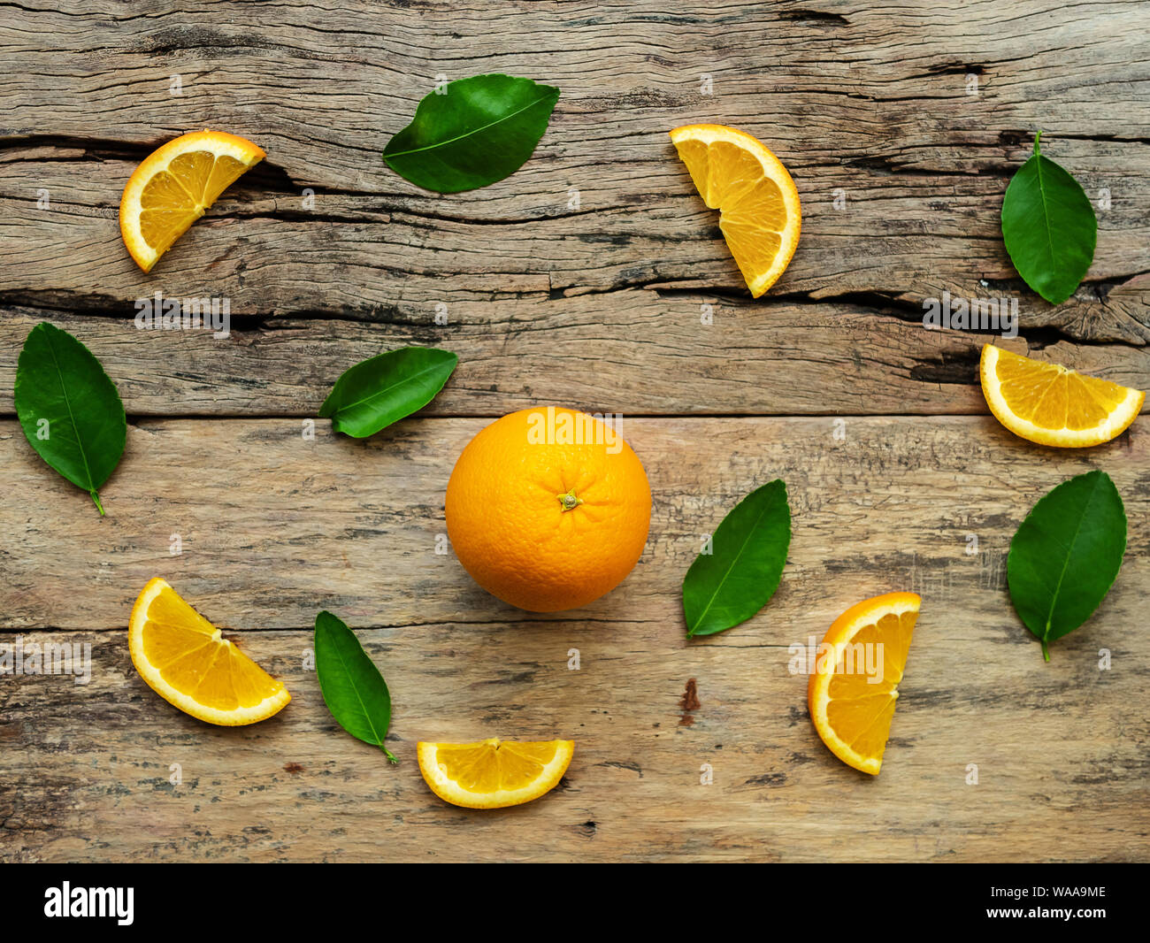 Zusammensetzung der Schichten, ganze orange Früchte mit grünen Blättern auf hölzernen Hintergrund. top View Stockfoto