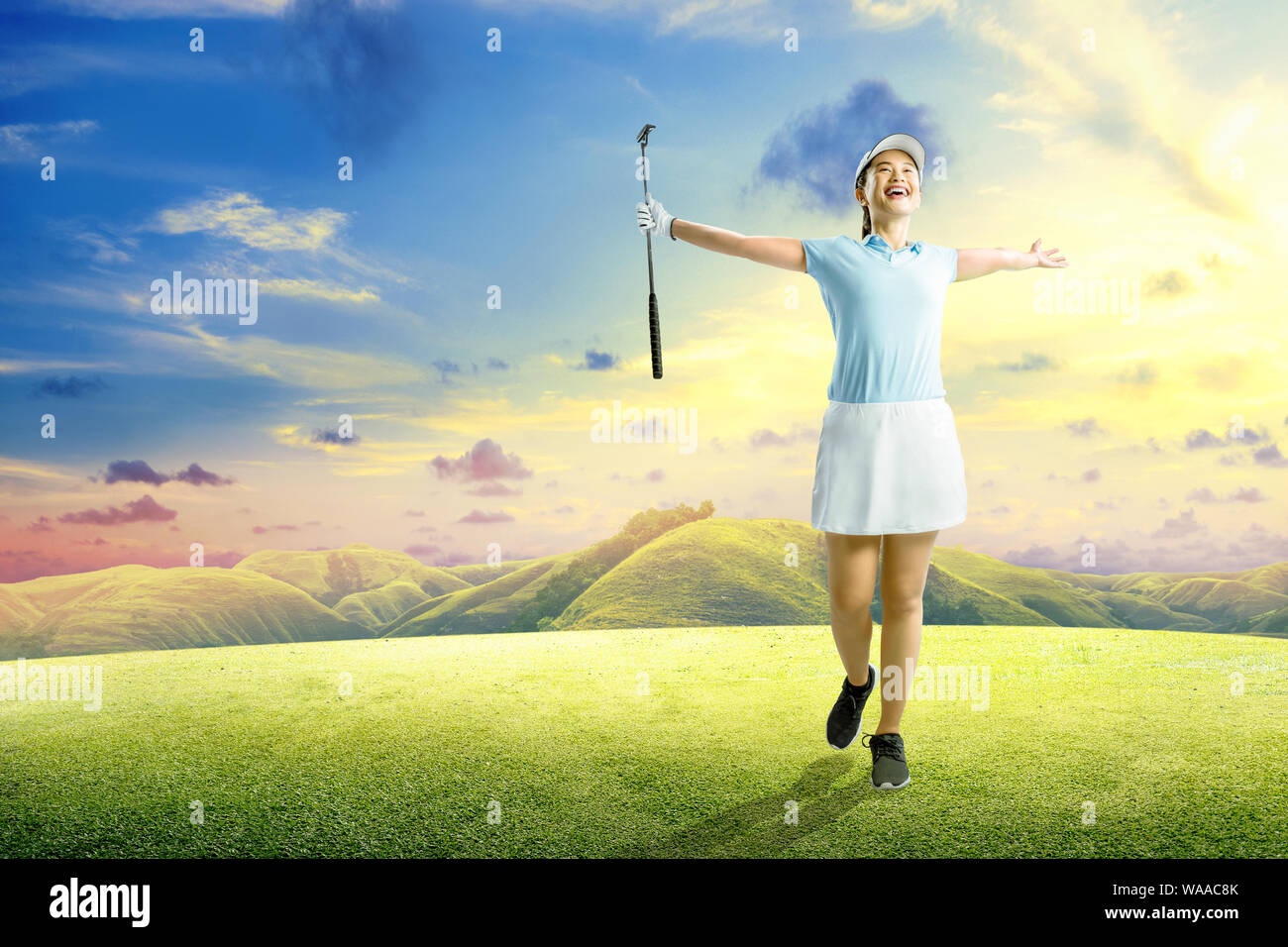Asiatische Frau mit dem Putter Golf Club mit einem glücklichen Ausdruck auf der grünen Golfplatz Stockfoto