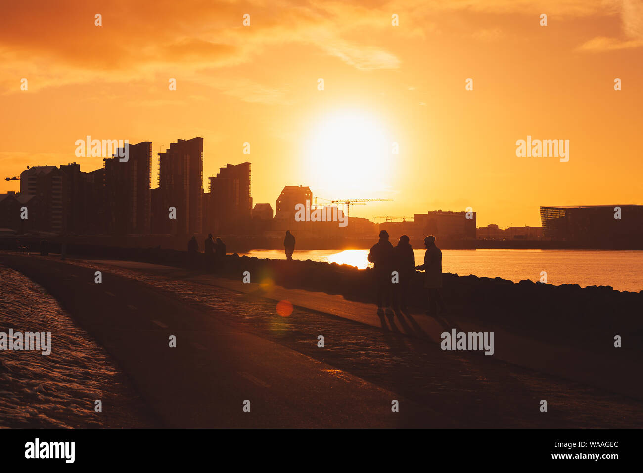 Reykjavik, Island - 3. April 2017: Silhouette Skyline von Reykjavik in hellem Sonnenlicht, die Hauptstadt von Island am Abend. Touristen zu Fuß auf dem c Stockfoto