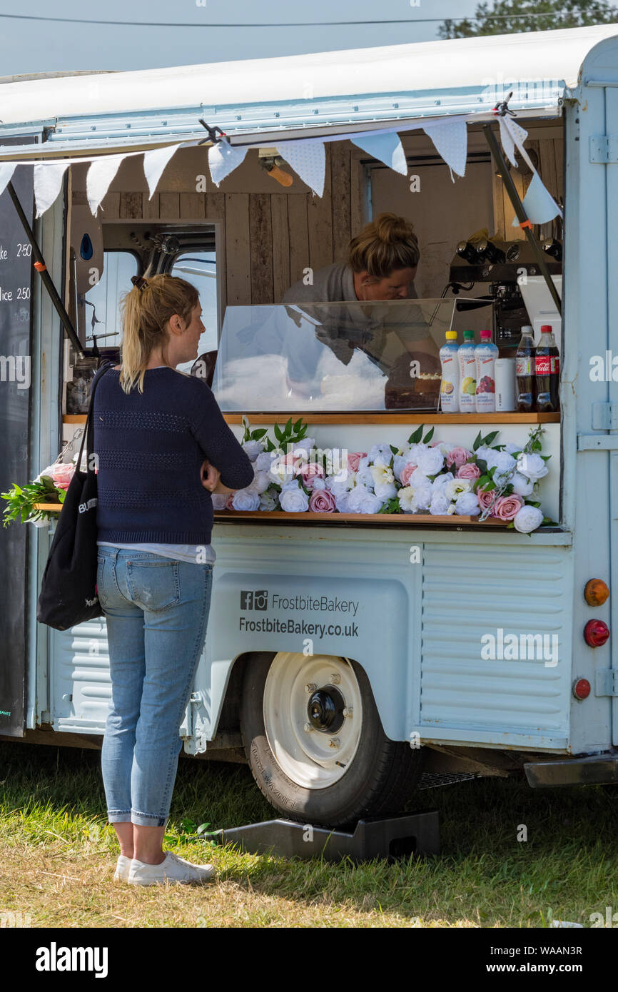 Eine junge Frau, bestellen einen Kaffee aus einer mobile Gastronomie van auf ein Land zeigen. Stockfoto
