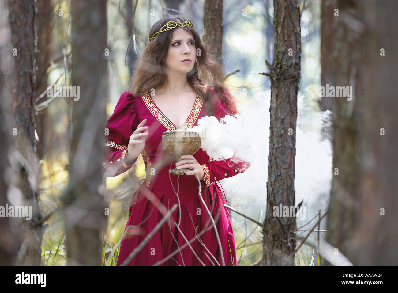 Frau in einem roten Kleid Casting einen Zauber mit Rauch Stockfoto