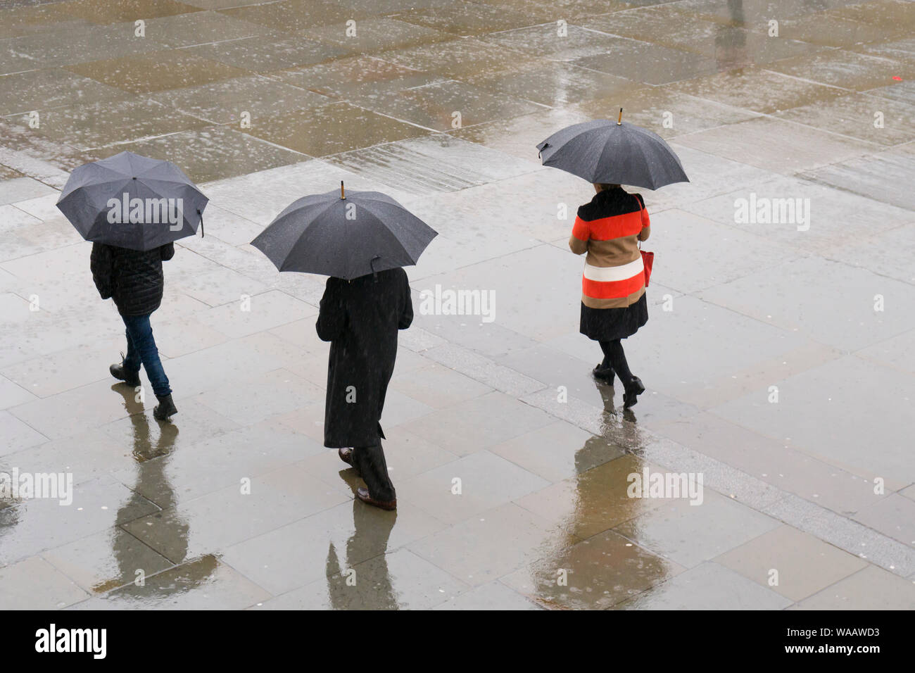 Menschen zu Fuß im Regen, Trafalgar Square, London, Großbritannien. Stockfoto