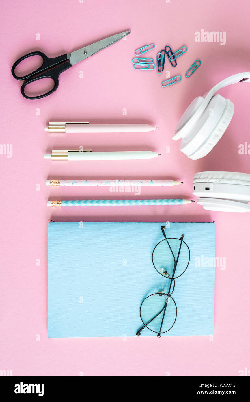 Kugelschreiber, Bleistifte, Clips, Schere, Kopfhörer, Brillen und blau Notebook Stockfoto