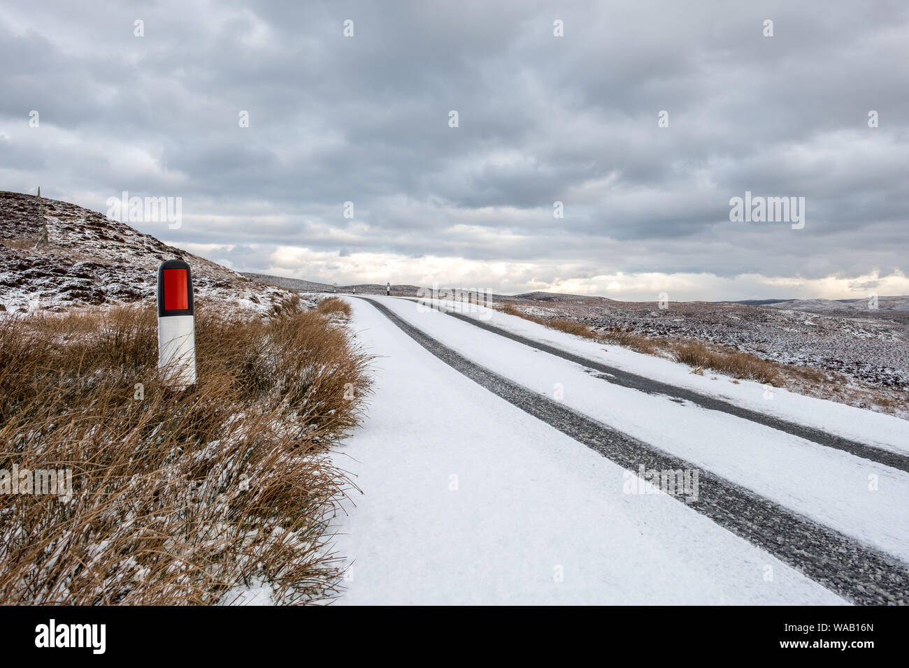 Deutliche Spuren an einem verschneiten Straße in ländlicher Umgebung mit einem stürmischen Himmel und Raum für Kopie Stockfoto