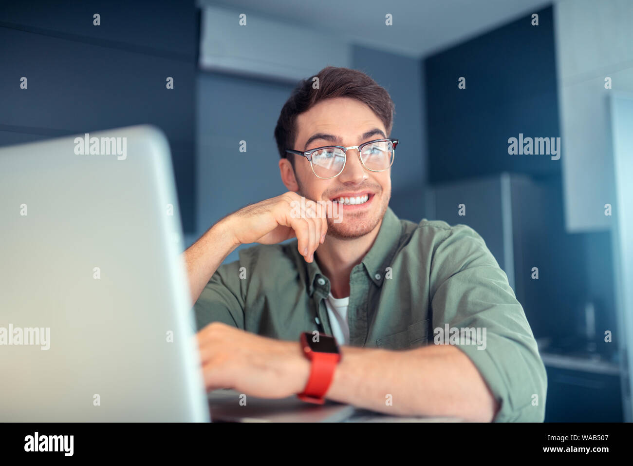 Schöner Mann lächelnd während der Arbeit am Laptop Stockfoto