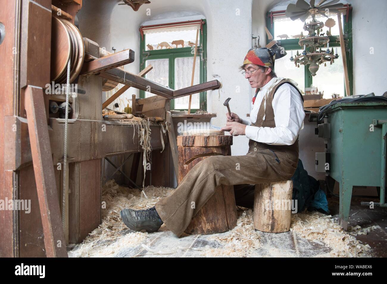 Seiffen, Deutschland. 17 Aug, 2019. Reifen Dreher Christian Werner teilt  eine Holz- Tier, eine so genannte Leer, aus eingraviertem Holz- ring mit  einem Messer und Hammer in seiner Werkstatt auf seiner Drehbank.