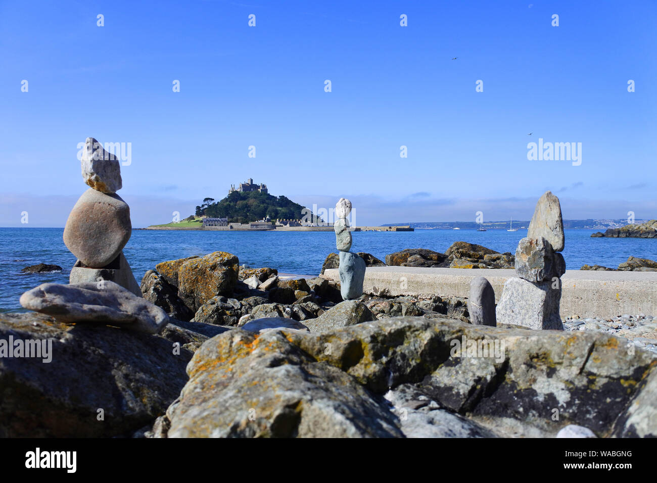 Balancing Steine am Strand von Marazion, Cornwall mit St. Michael's Mount im Hintergrund - Johannes Gollop Stockfoto