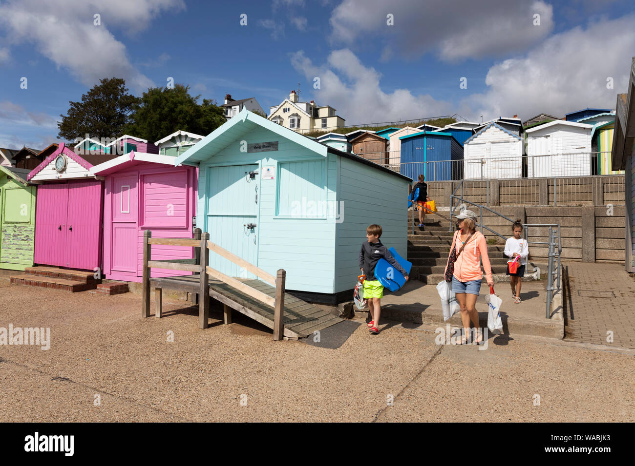 Bunte Badehäuschen entlang der Strandpromenade mit Familie auf den Weg zum Strand, Walton-on-the-Naze, Essex, England, Vereinigtes Königreich, Europa Stockfoto