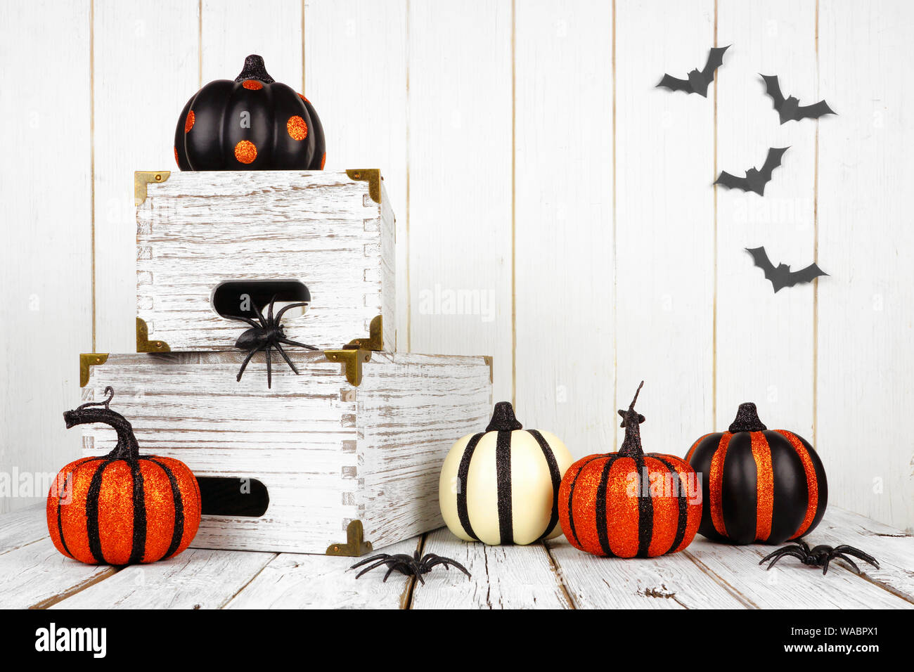Schwarz, Weiß und Orange Halloween Dekoration gegen einen weißen Holz Hintergrund Stockfoto