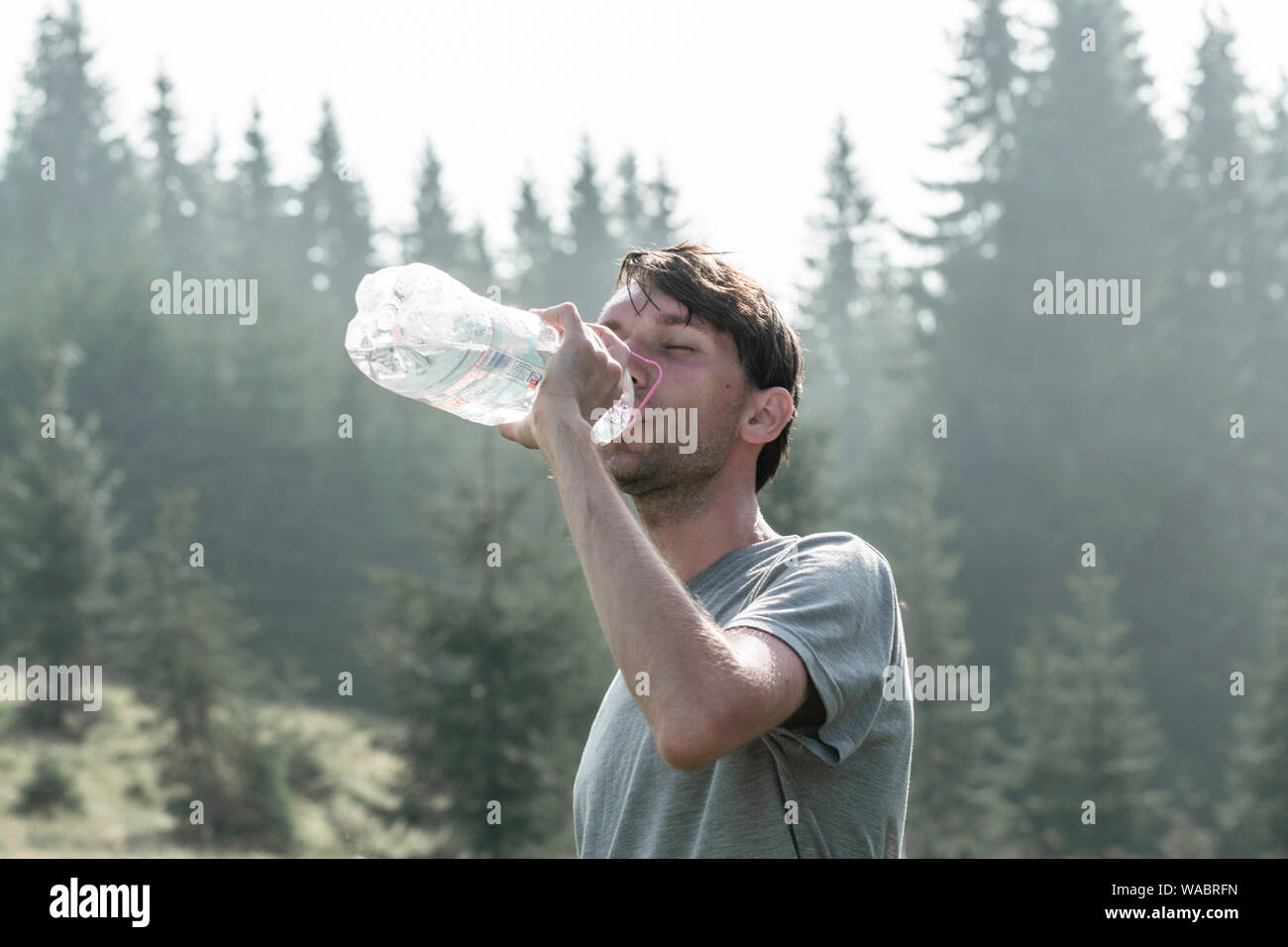 Jungen trinken frisches Wasser nach der langen Wanderung im Wald Stockfoto