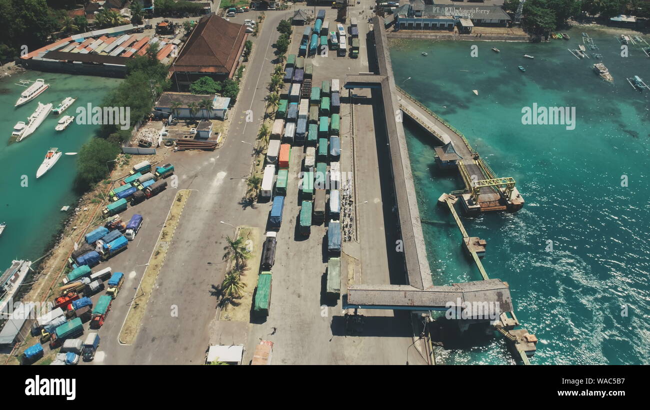 Antenne Top Drone Ansicht der Insel Harbour Hafen mit vielen Lkw bereit für die Fähre einschiffen. Crystal Meer Wasser Landschaft in tropischen Insel Bali, Indonesien Stockfoto