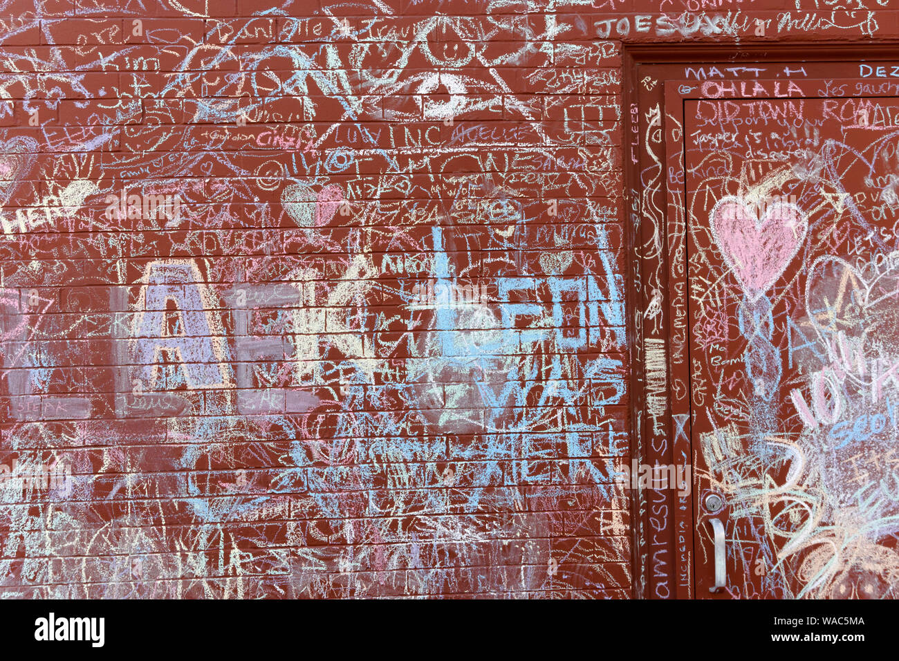 Red brick wall eines Gebäudes in bunte Kreide Graffiti an der Mount Pleasant Viertel von Vancouver, BC, Kanada abgedeckt Stockfoto