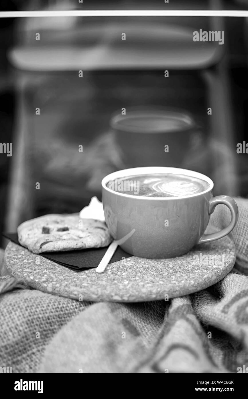 Kaffee mit Milchschaum und Kaffeebohnen in einem Sack auf Beutel Stockfoto