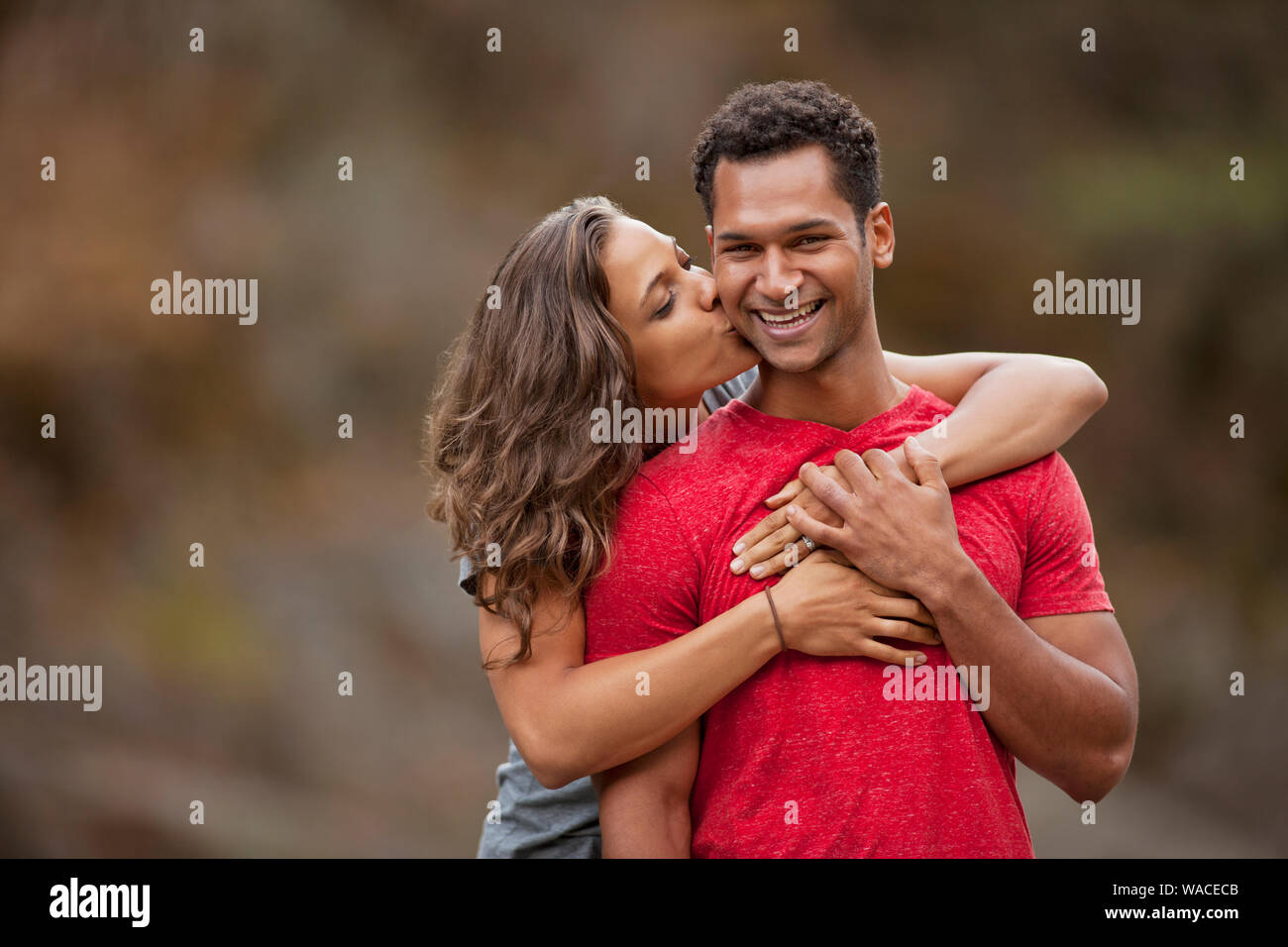 Porträt eines lächelnden jungen Mann auf die Wange geküsst von seiner Freundin. Stockfoto