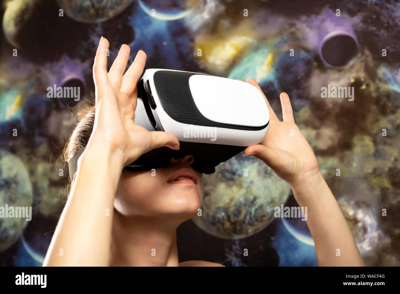 Eine Frau ist auf der Suche durch Virtual Reality im Raum. Raum Hintergrund Stockfoto