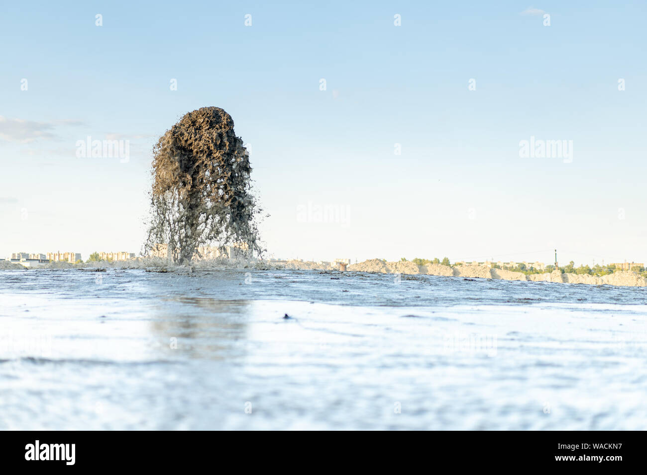 Ein großer Brunnen Wasser gemischt mit Sand, dass Beats aus einem metallrohr vor blauem Himmel. Sand Mining. Schwemmland von Mineralien. Stockfoto