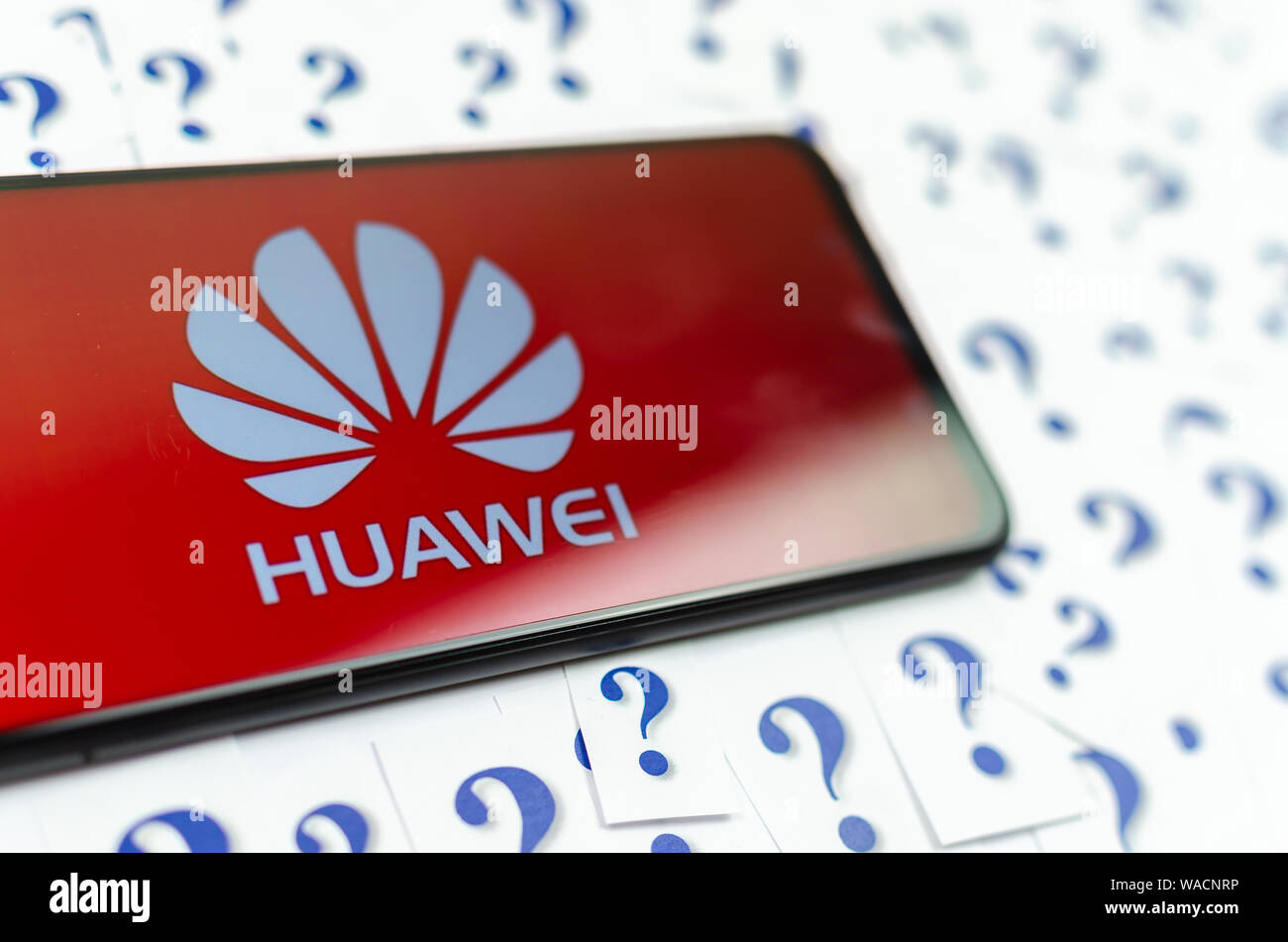 HUAWEI HUAWEI Logo auf dem Smartphone und eine Menge Papier Fragezeichen um. Die konzeptuellen Foto über Zukunft der Tech giant in den USA. Stockfoto