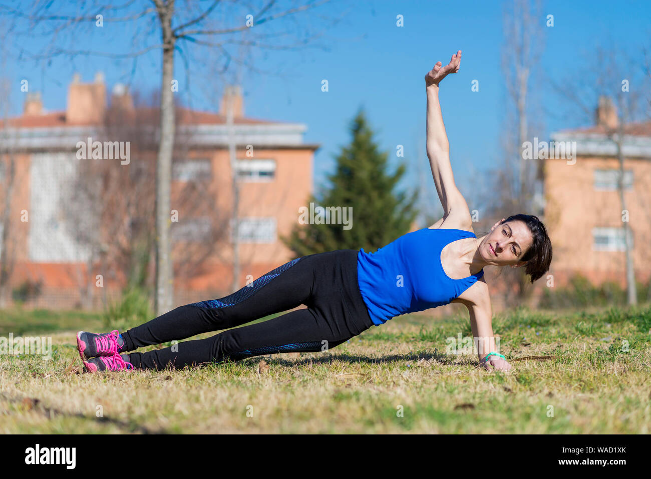 Frau mit Pferdeschwanz stretching auf einem Park Gras an einem sonnigen Tag Stockfoto