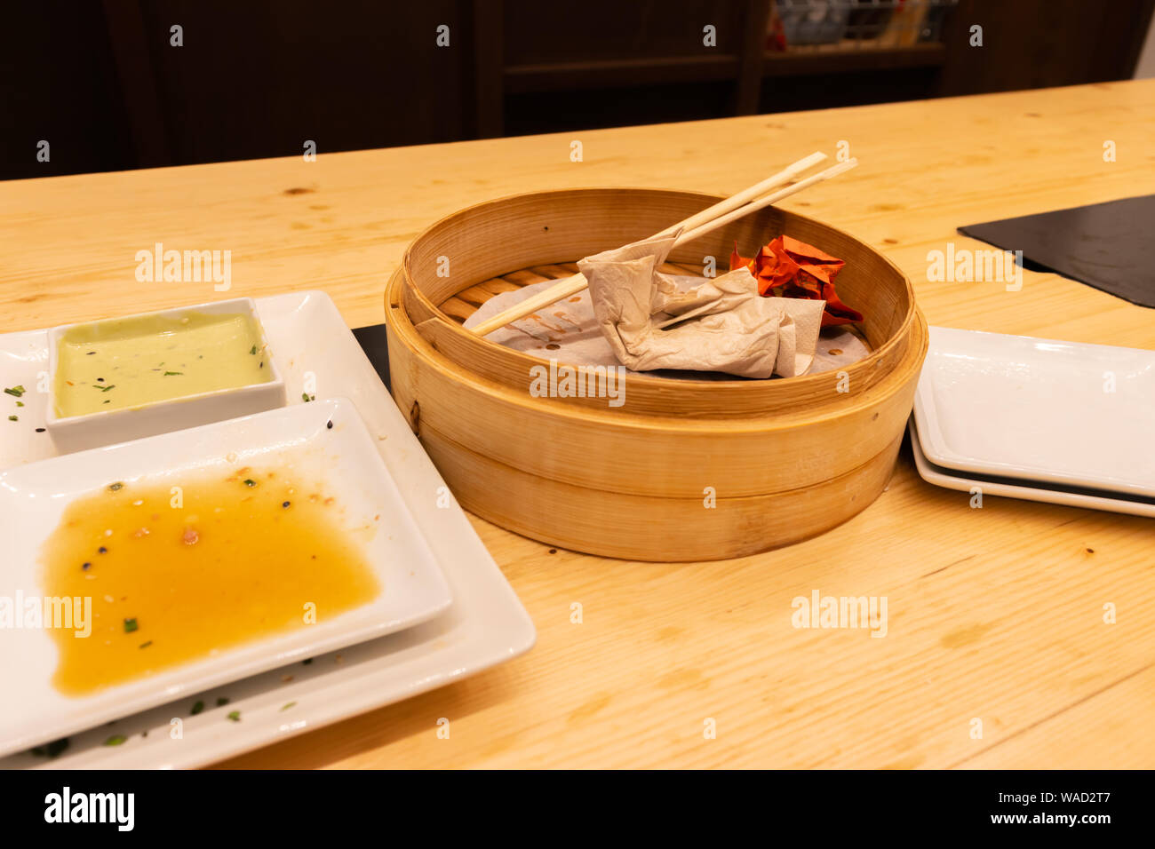 Die leeren Teller und hölzernen Dampfer von gedämpften Teigtaschen auf einem Holztisch mit Stäbchen in einem asiatischen Restaurant oder chinesische Bar mit Knödeln Stockfoto