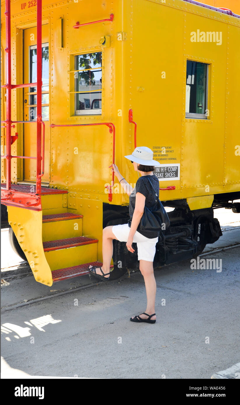 Sacramento. Lady trägt Shorts und Sonnenhut an Board einer gelben Kabinenbahn in der Altstadt von Sacramento. Stockfoto