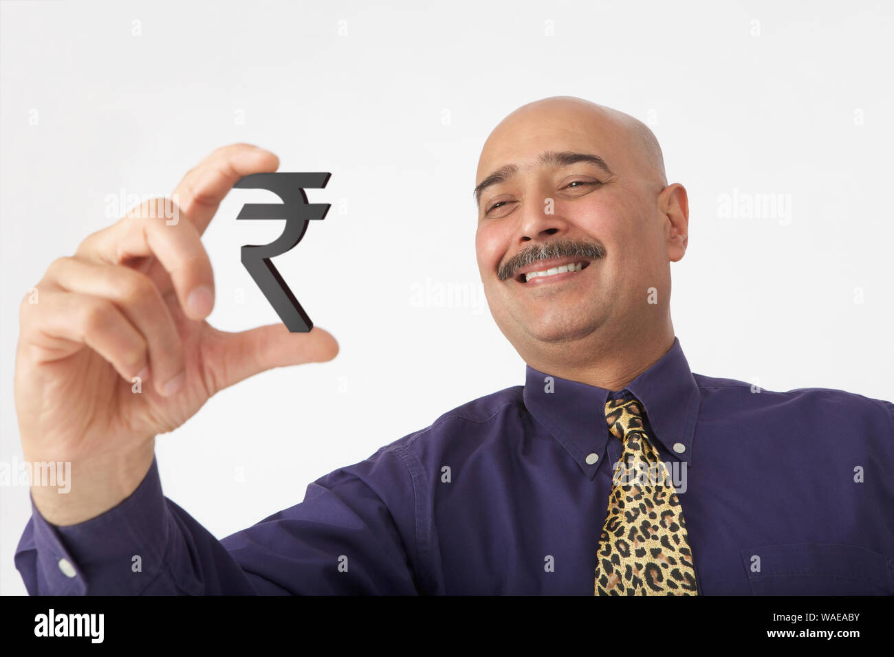 Geschäftsmann zeigt Rupie-Symbol und lächelt Stockfoto