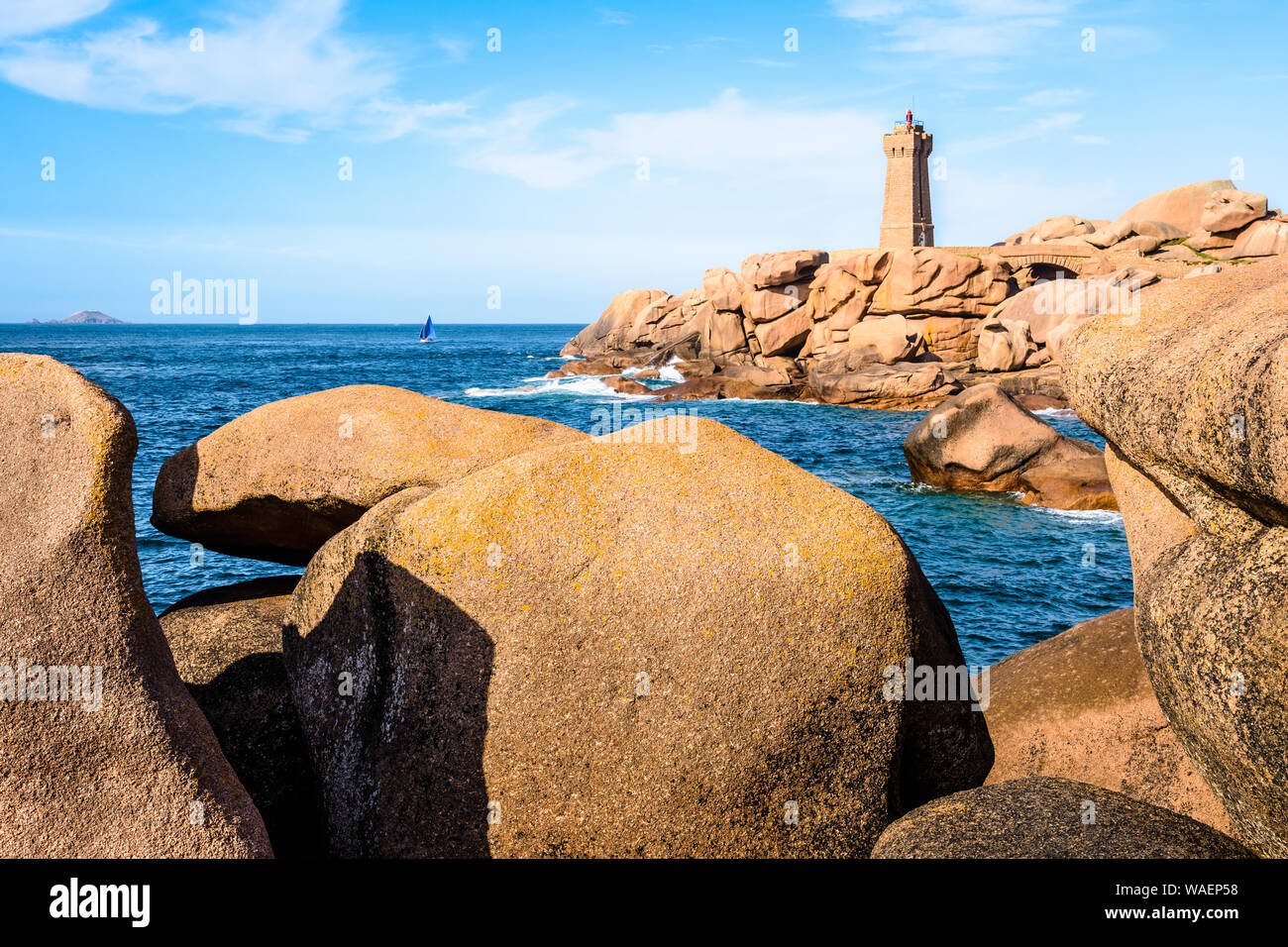 Die Ploumanac'h Leuchtturm, genannt, Ruz, an der Küste des Rosa Granits in Perros-Guirec, Bretagne, mit großen Granitfelsen im Vordergrund. Stockfoto
