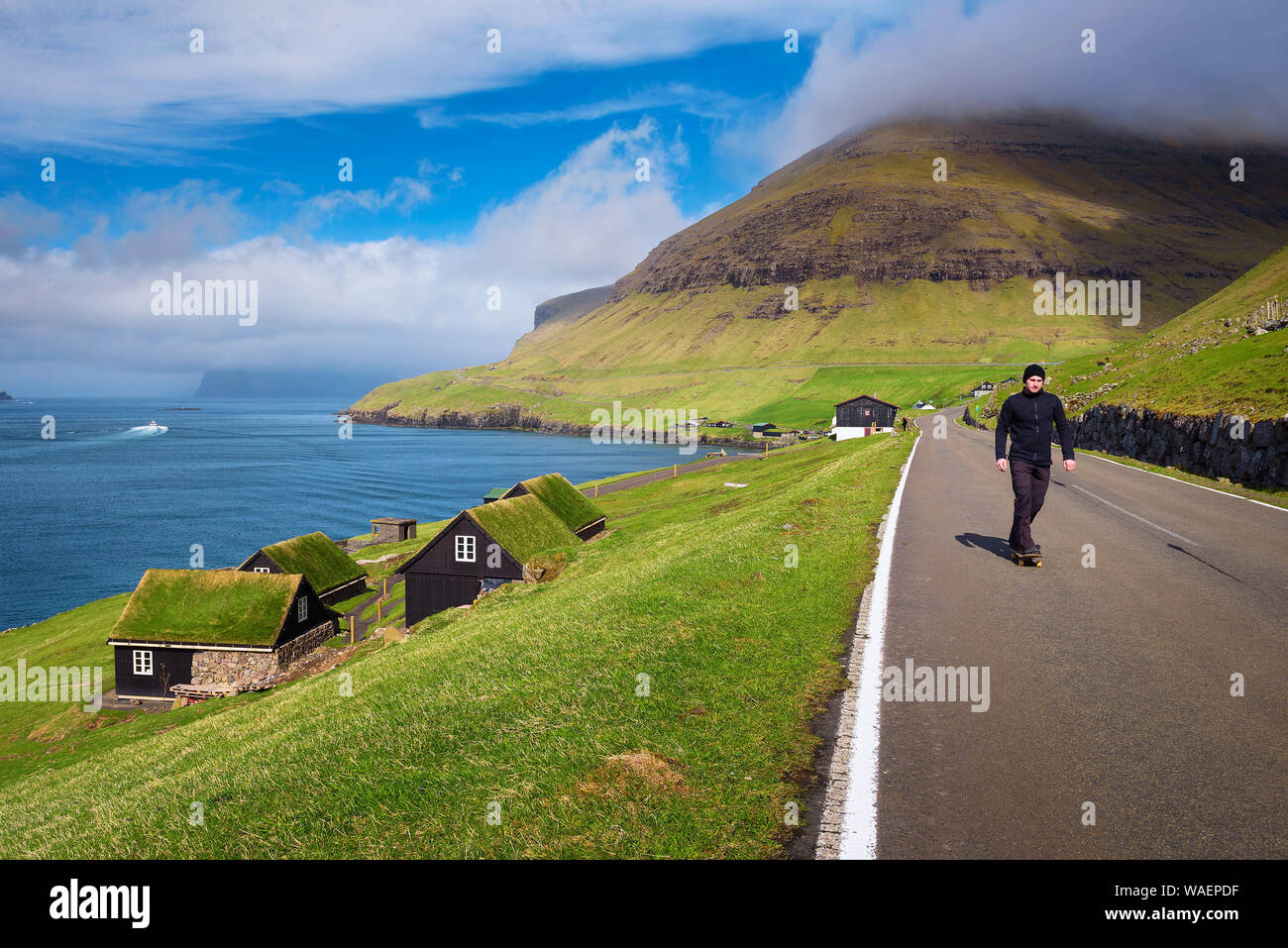 Skater, der auf einem Skateboard durch das Dorf Bour auf den Färöer Inseln Stockfoto