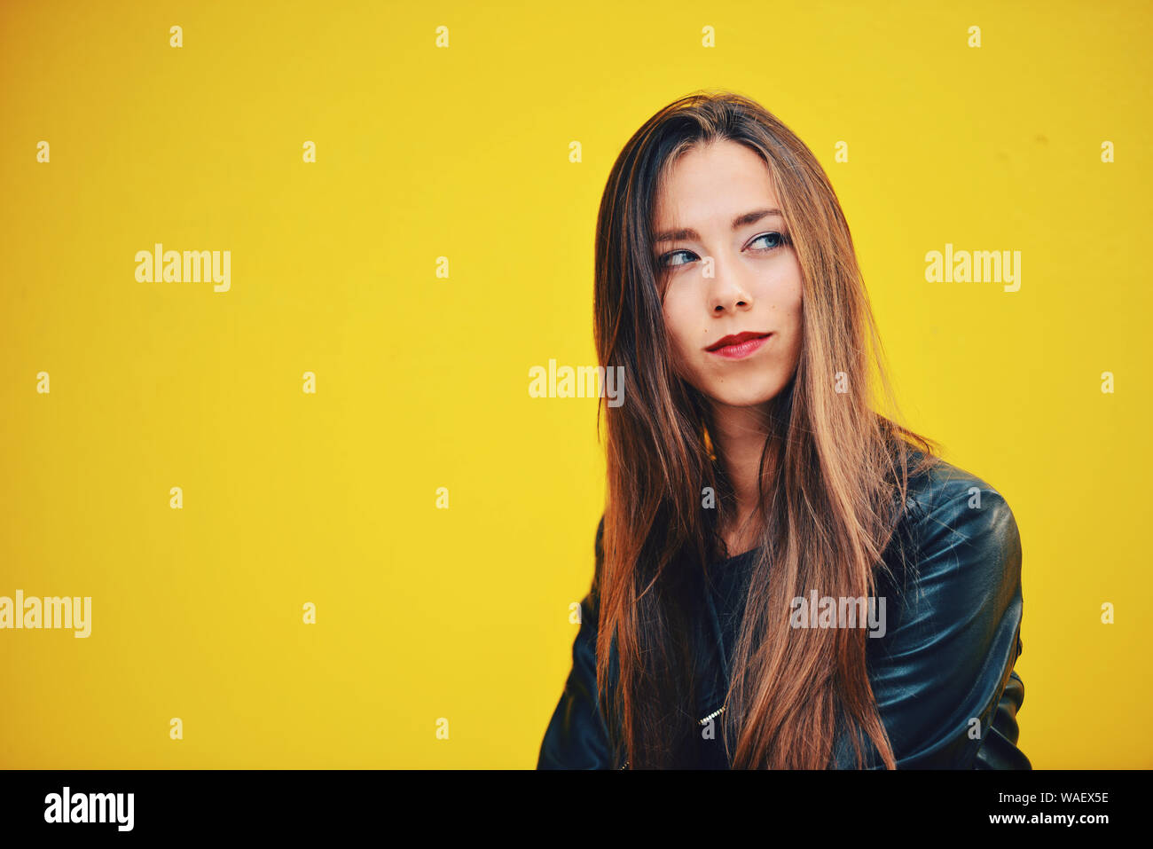 Schöne junge Frau in schwarzem Leder Jacke gegen gelben Hintergrund Stockfoto